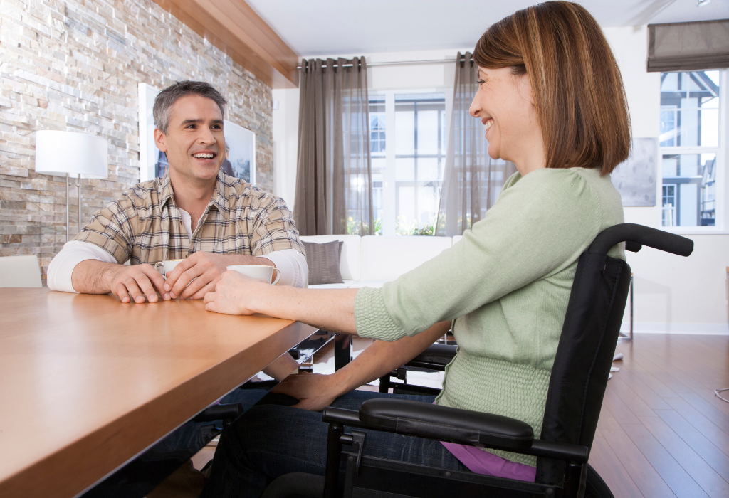 Woman in wheelchair speaking with man at table